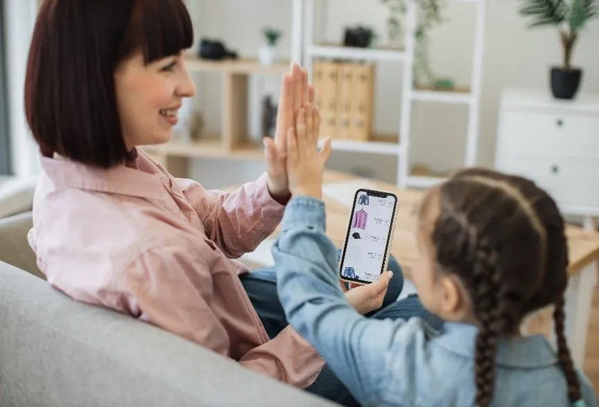 スマートフォンを見ながらハイタッチする親子
